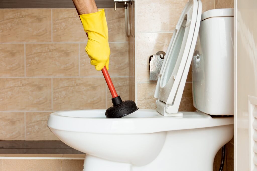 Licensed plumber using plunger to clear gurgling toilet in Sydney
