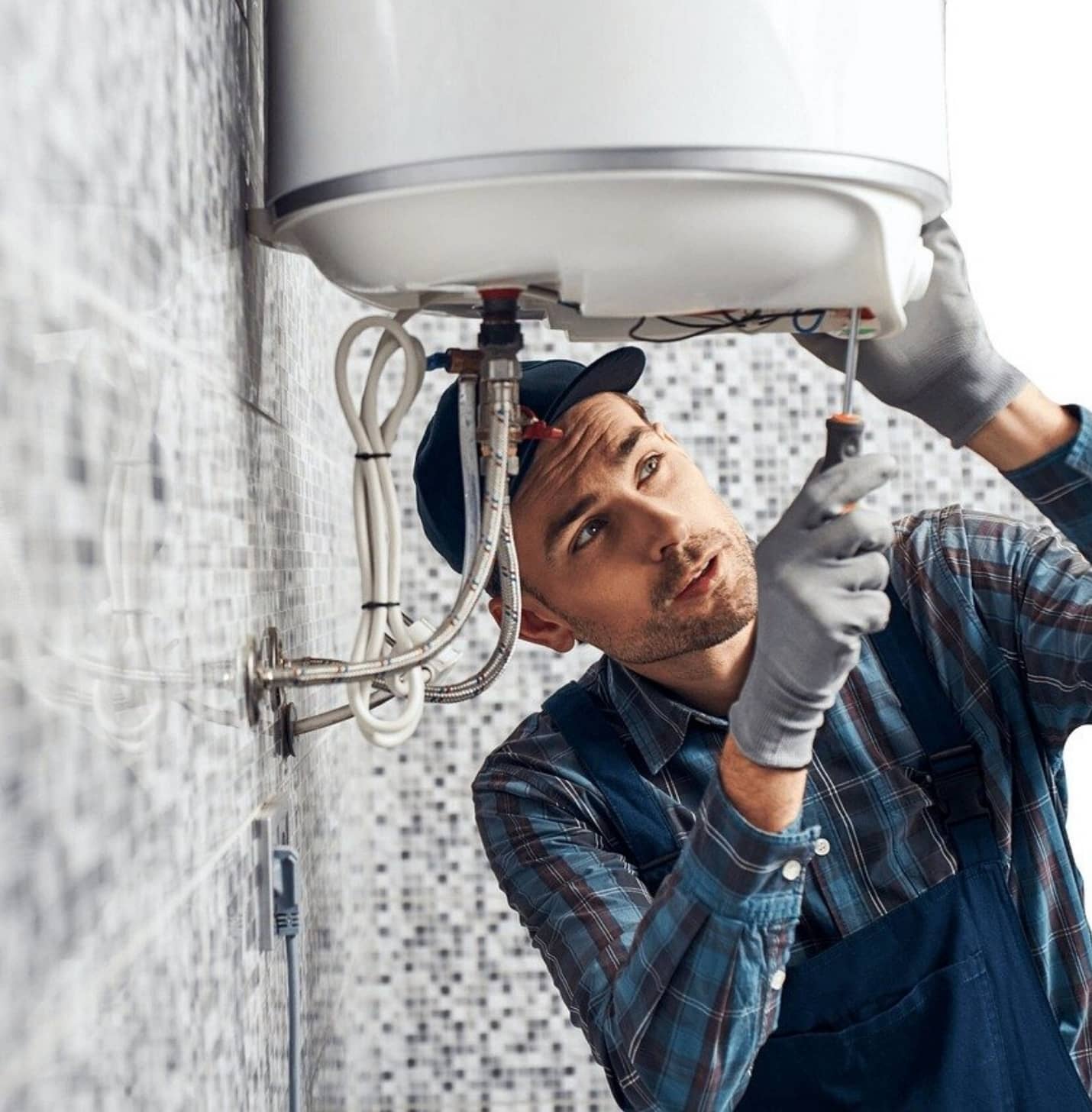Skilled plumbing services shown by a man repairing a wall-mounted water heater with gloves and a screwdriver.